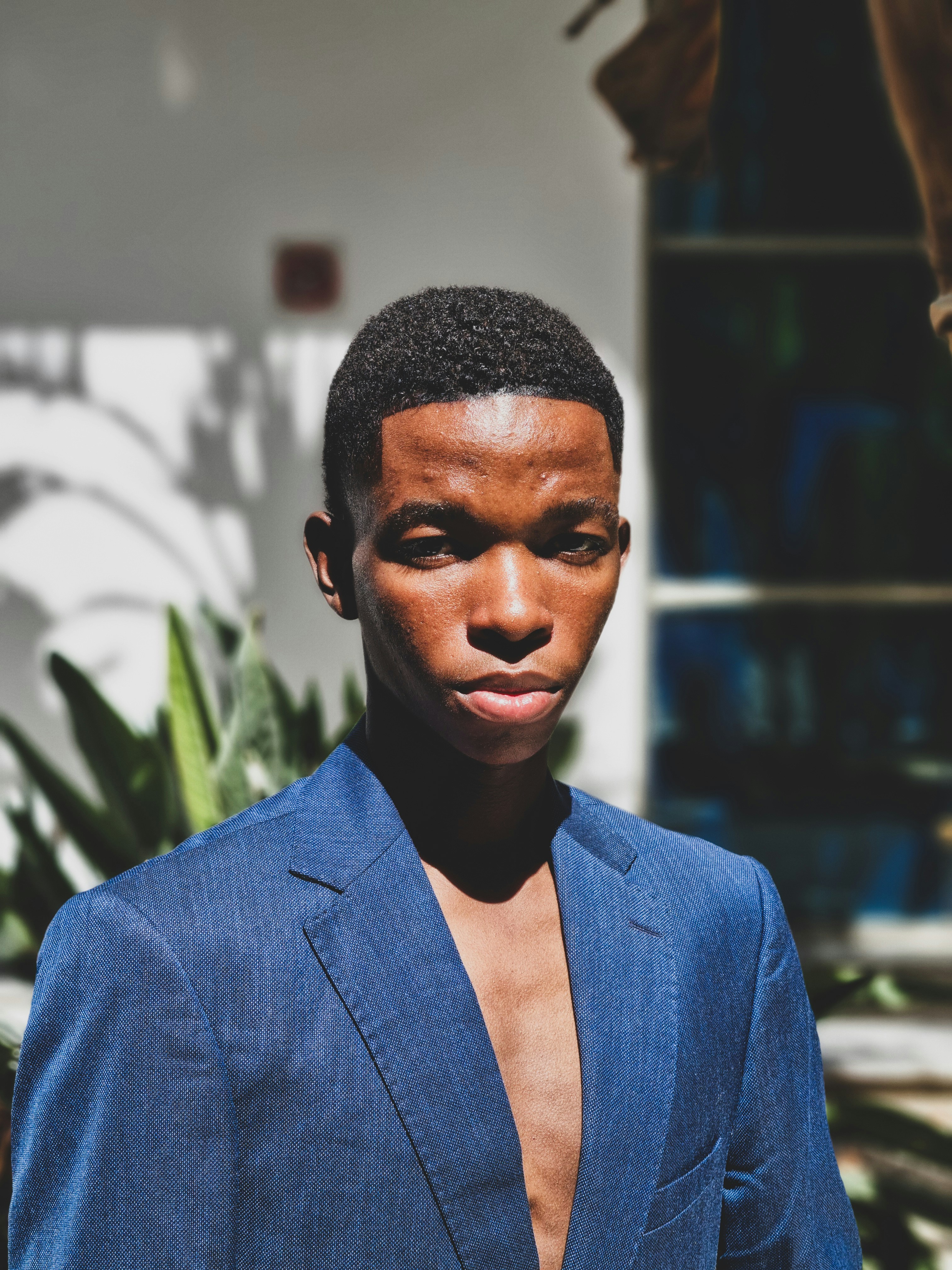 A young man poses outdoors in a blue blazer.