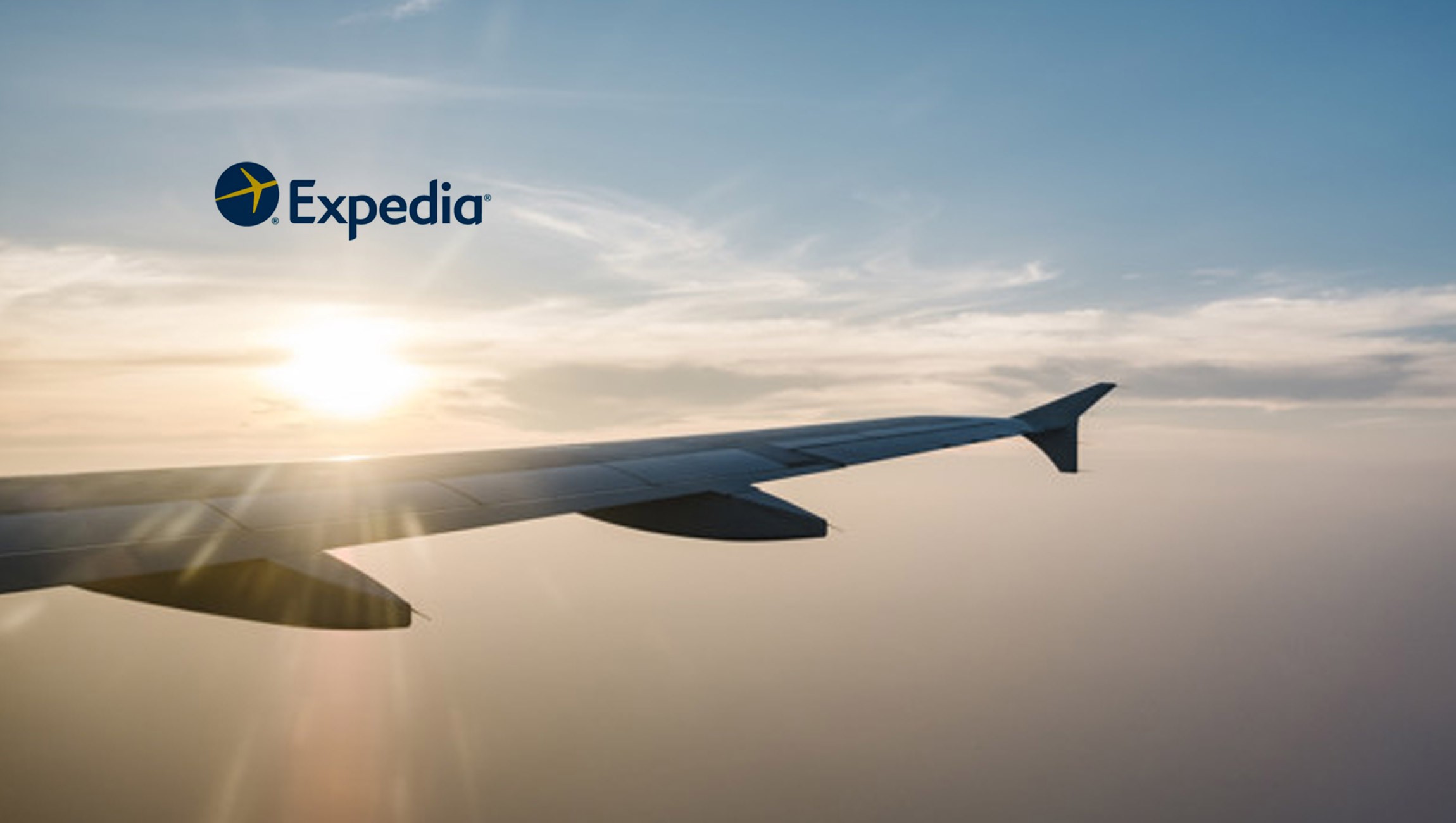 Sunny sky with the airplane wing in view, displaying the Expedia logo.
