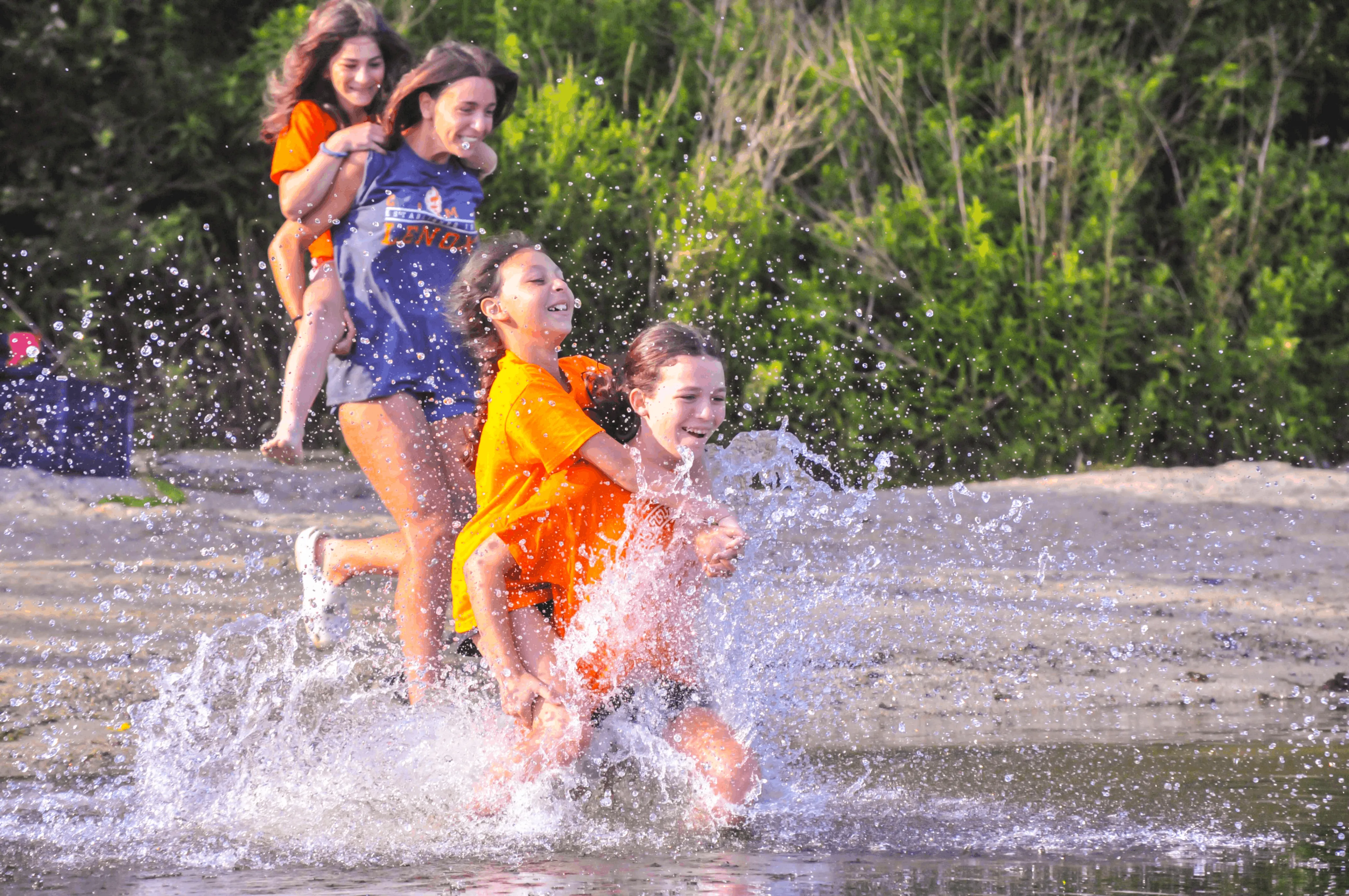 Campers running and splashing into the lake at Camp Lenox