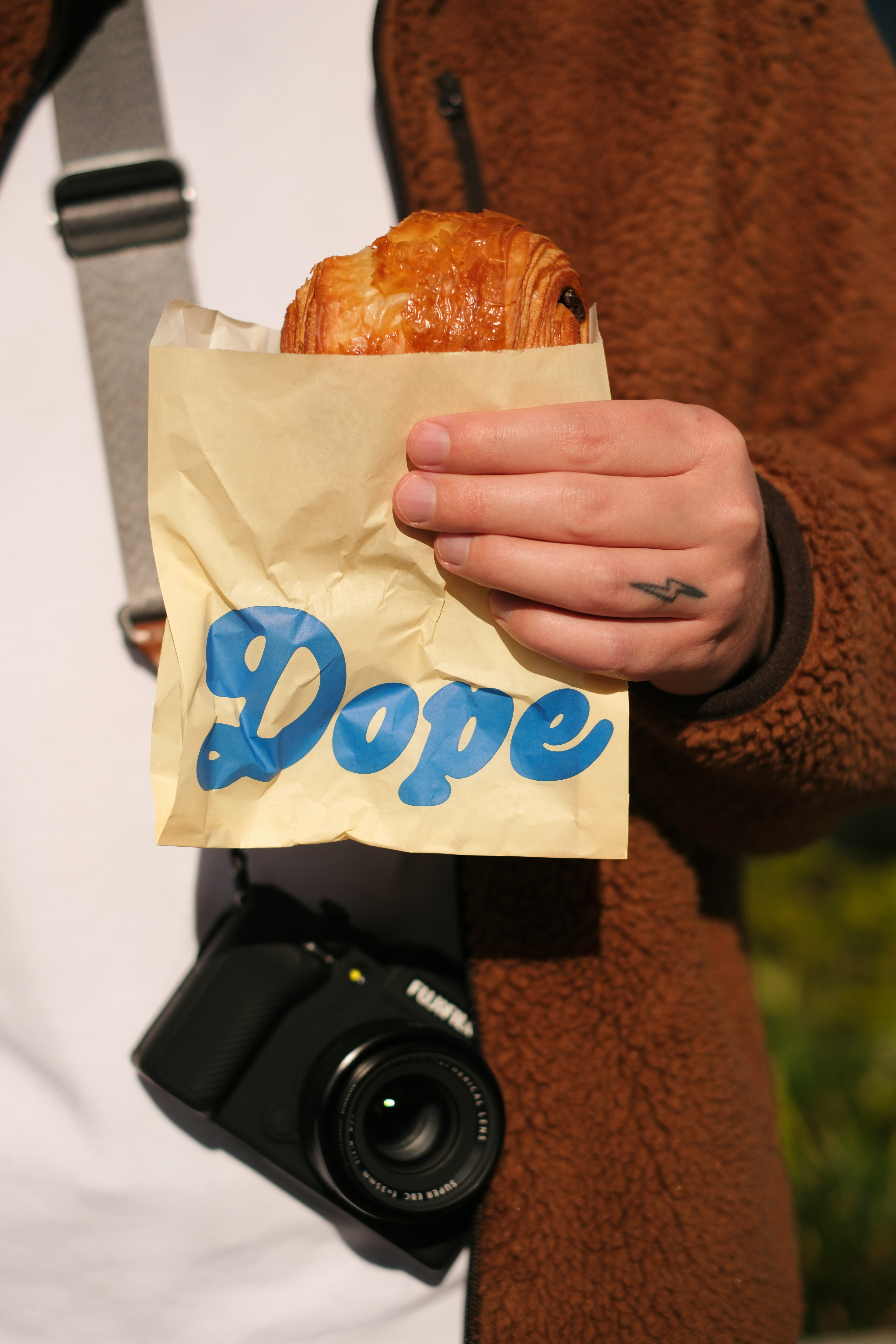 Person holding a croissant in a paper bag