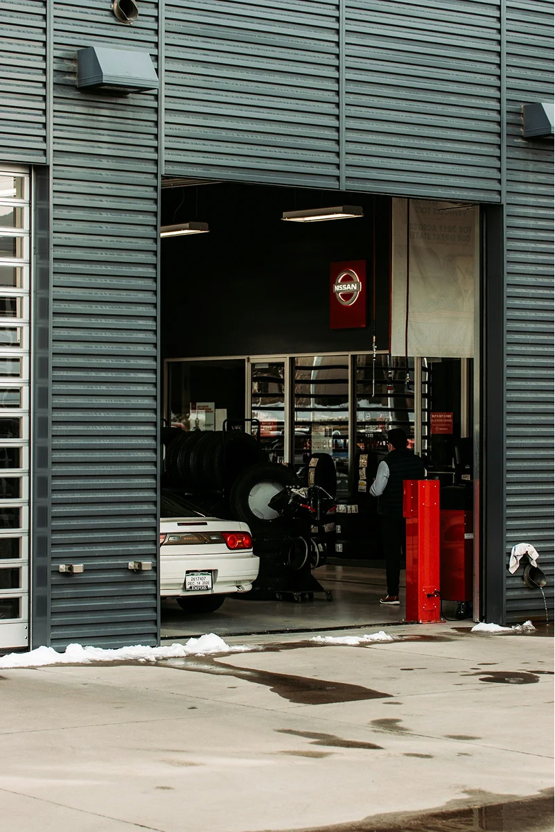 Classic black car viewed from the rear inside a dimly lit professional detailing garage