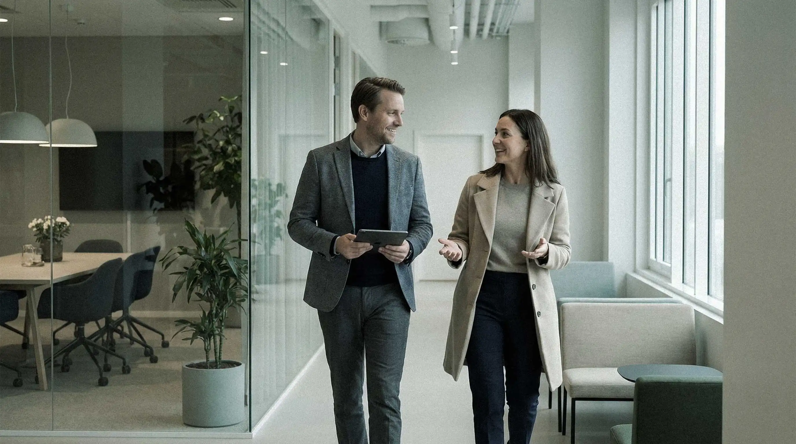 Two persons walking and talking in a modern office environment.