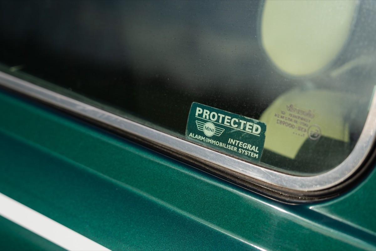 Close-up of a green car's window with a reflection and a small sticker visible inside.