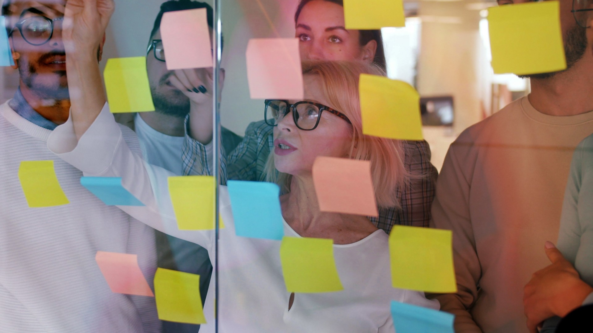 A group of people behind a glass window looking at sticky notes