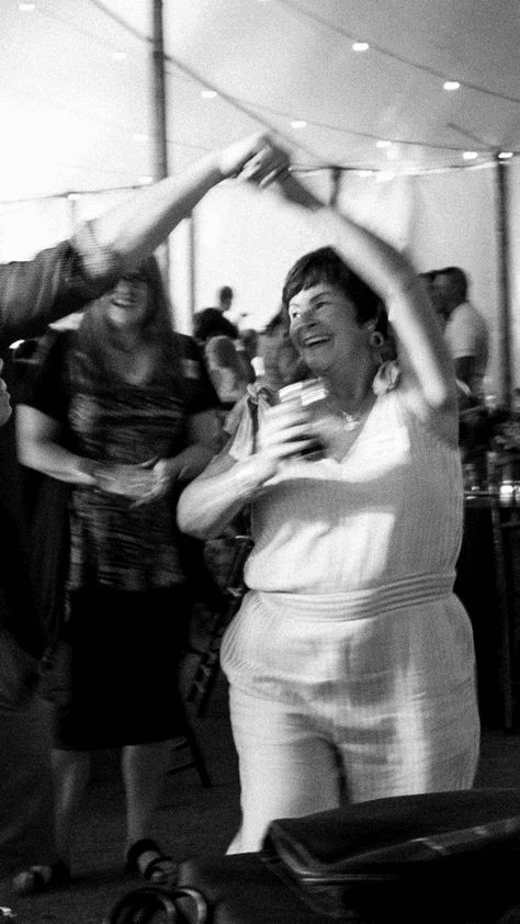 Candid wedding reception photo showing a woman dancing with joy, highlighting the spontaneous energy typical of documentary wedding photography.