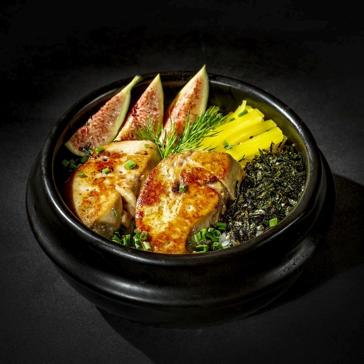 a person holding a black plate with slices of bacon on it