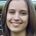 Smiling woman with brown hair outdoors.