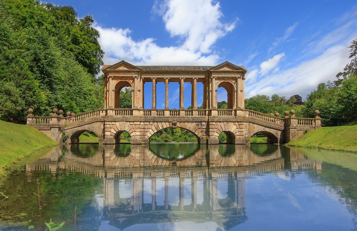 Palladian Bridge at Prior Park reflected in calm water, symbolising architectural structure, legacy, and continuity for distinguished families.