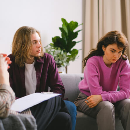 A man and a woman sitting next to each other while listening to their therapist