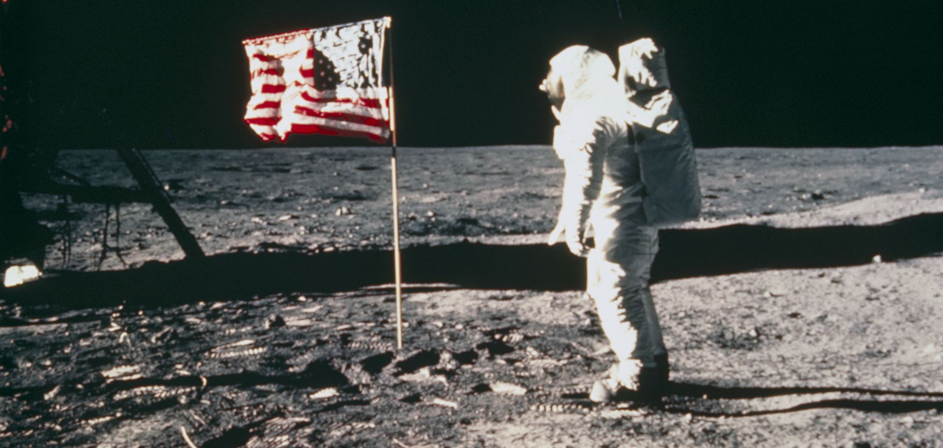 Apollo 11 astronaut standing on the lunar surface beside an American flag during the 1969 NASA moon landing