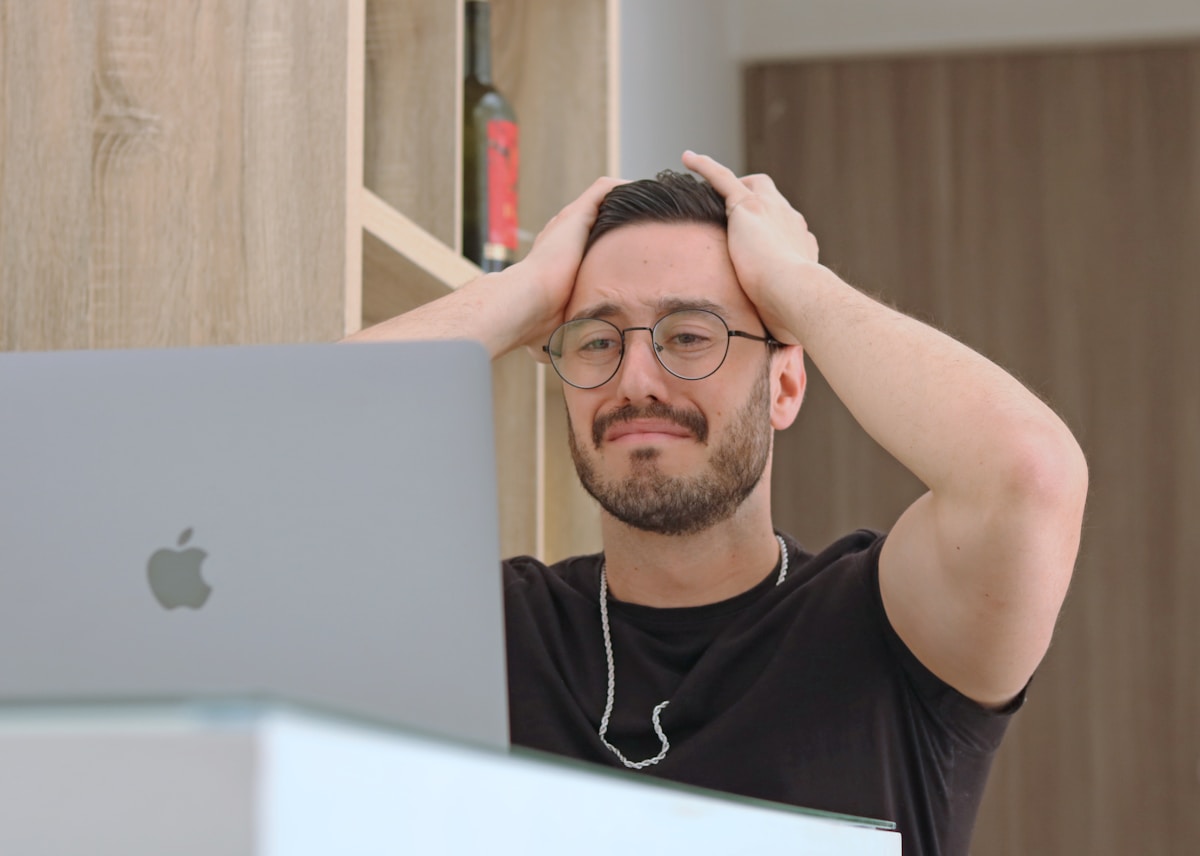 Personne perplexe devant un ordinateur portable, illustrant les erreurs de site web qui font fuir les clients, par Wendlia