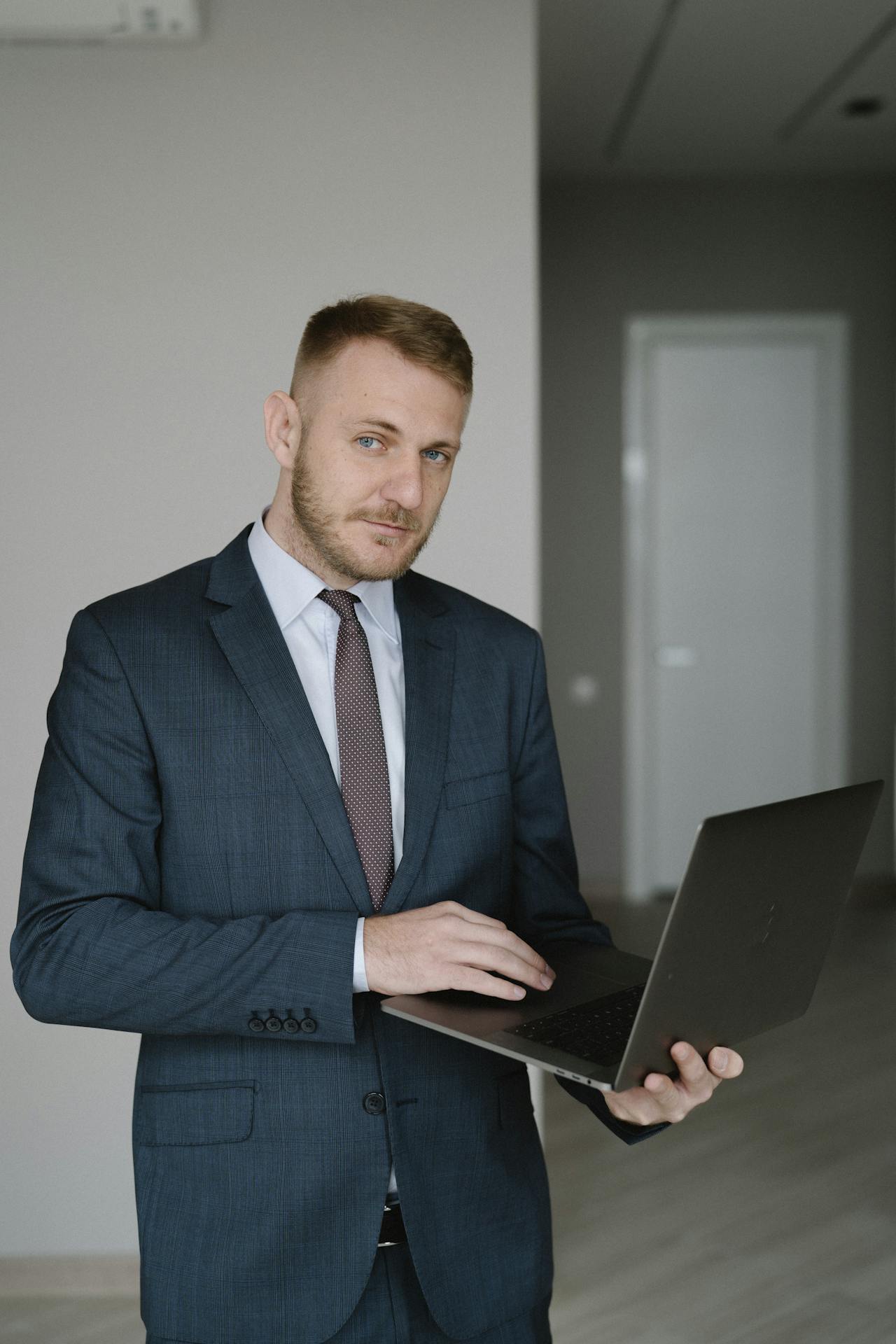 Man in Blue Suit Holding a Laptop