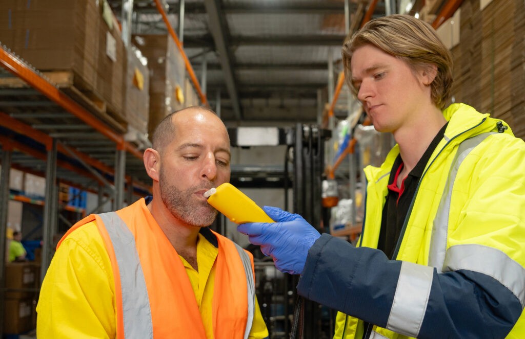 Trabalhadores fazendo teste de alcool na empresa.
