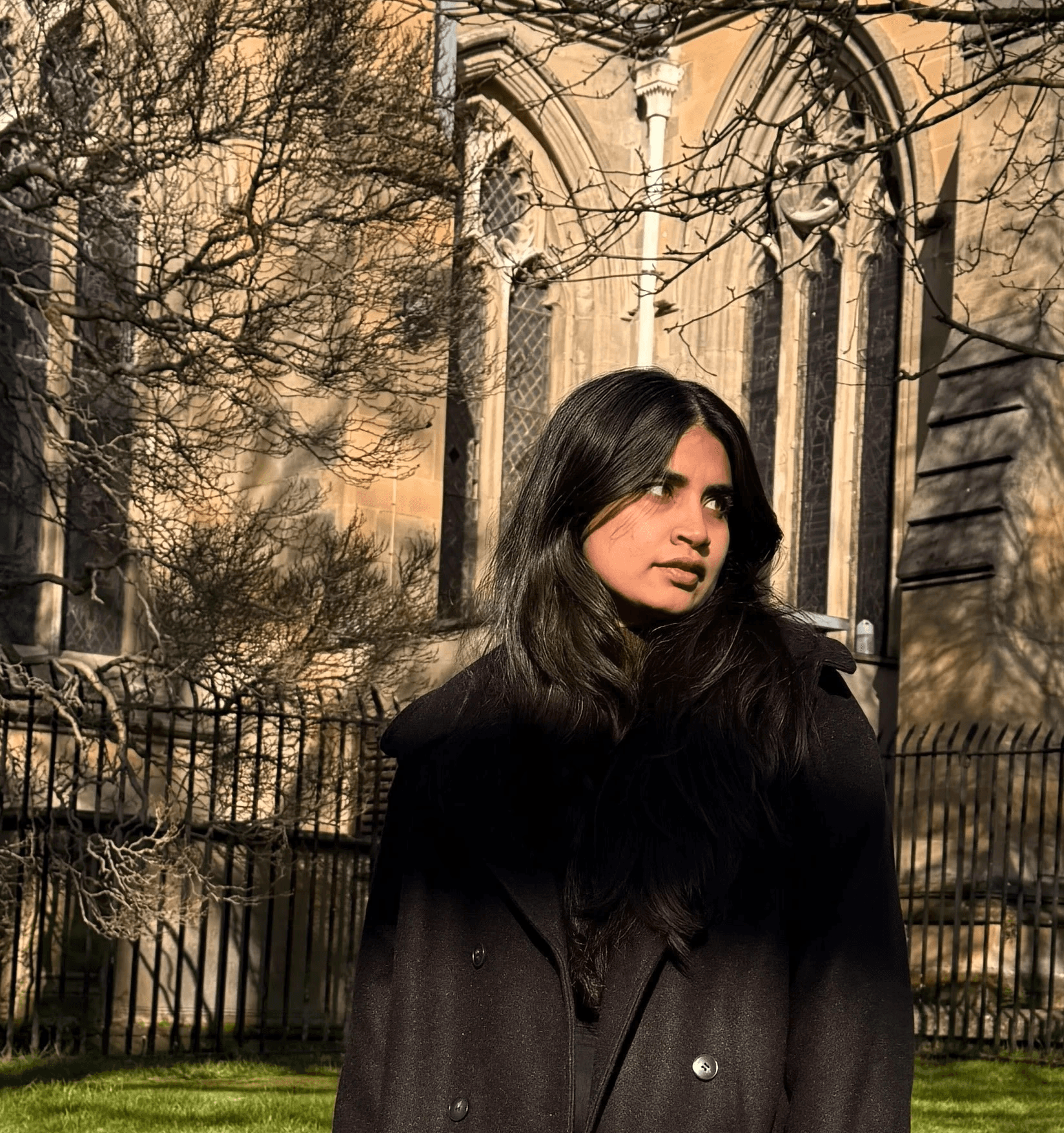 A thoughtful young person with dark hair gazes to the side, captured in soft black and white lighting.