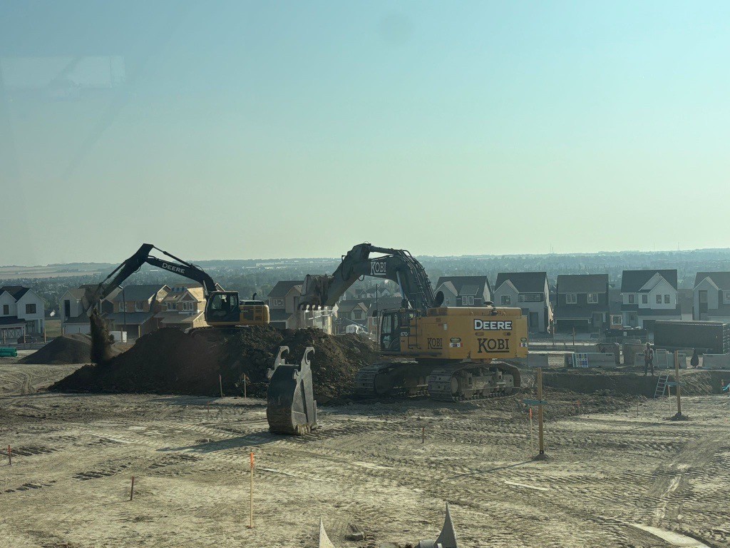 a yellow excavator on a hill with a blue sky in the background