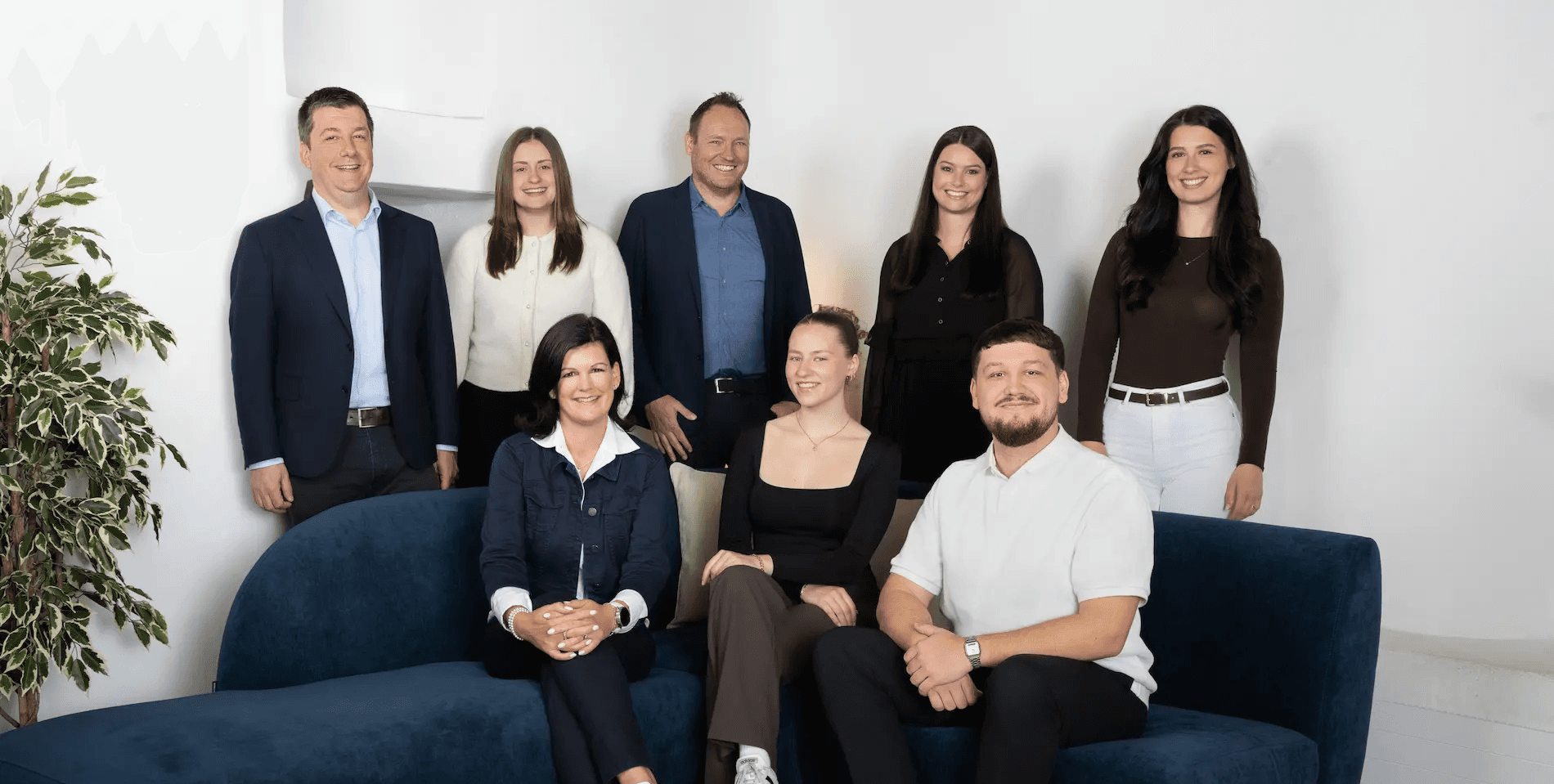 Gesamtes Team von Kocher Immobilien sitzt gemeinsam im Büro und lacht in moderner Umgebung