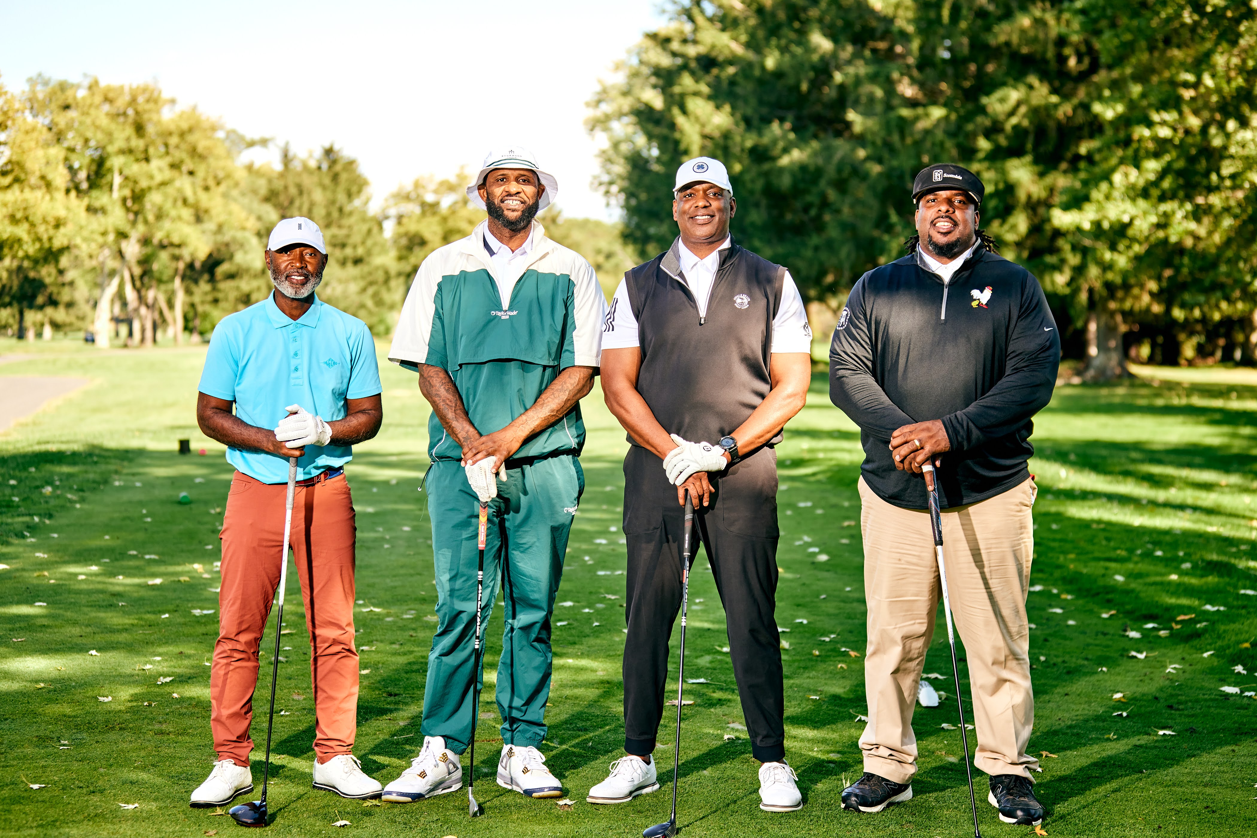 Four men stand with golf clubs on a golf course