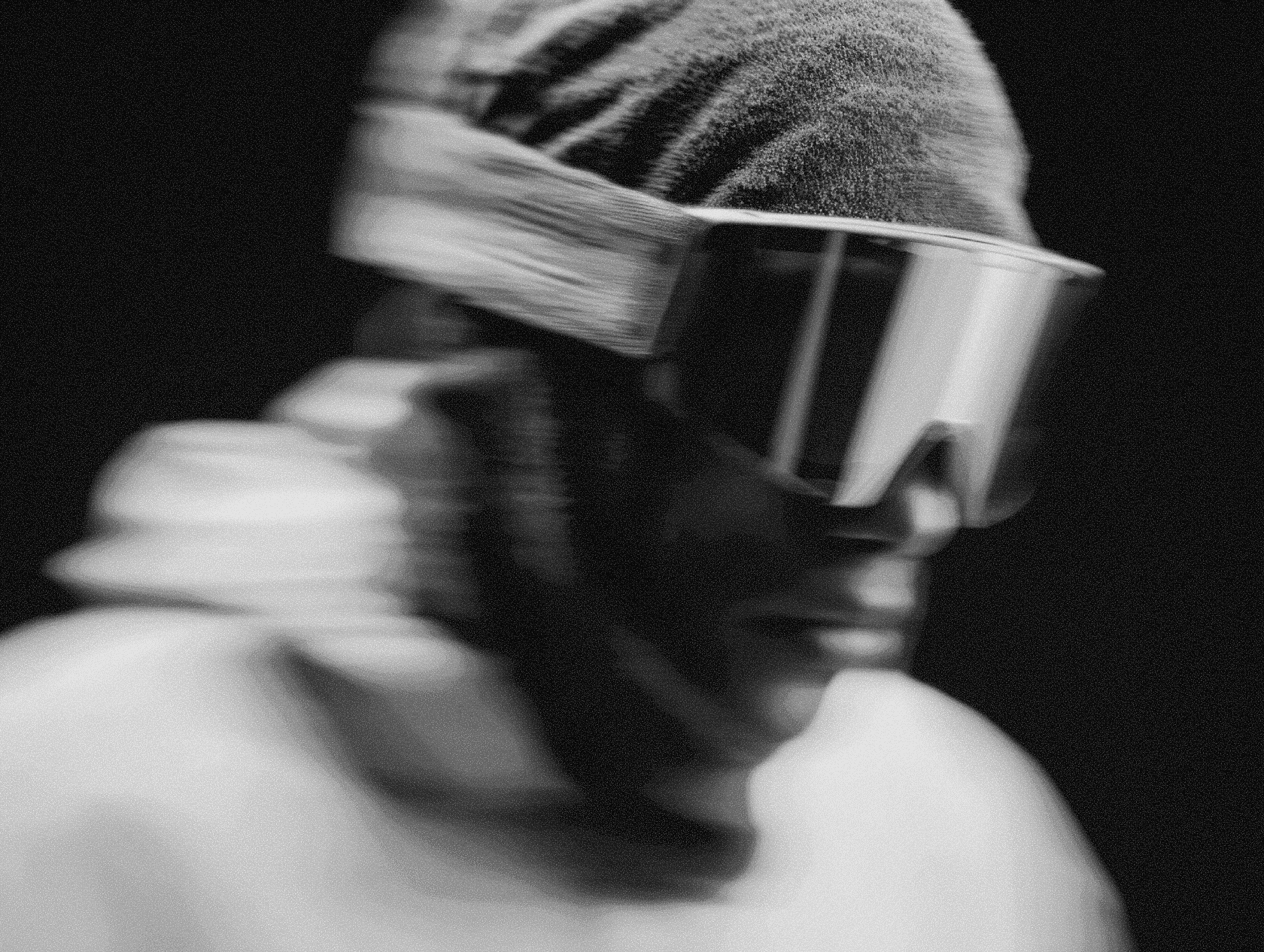 A side-angle close-up of a helmeted figure with mechanical strap details