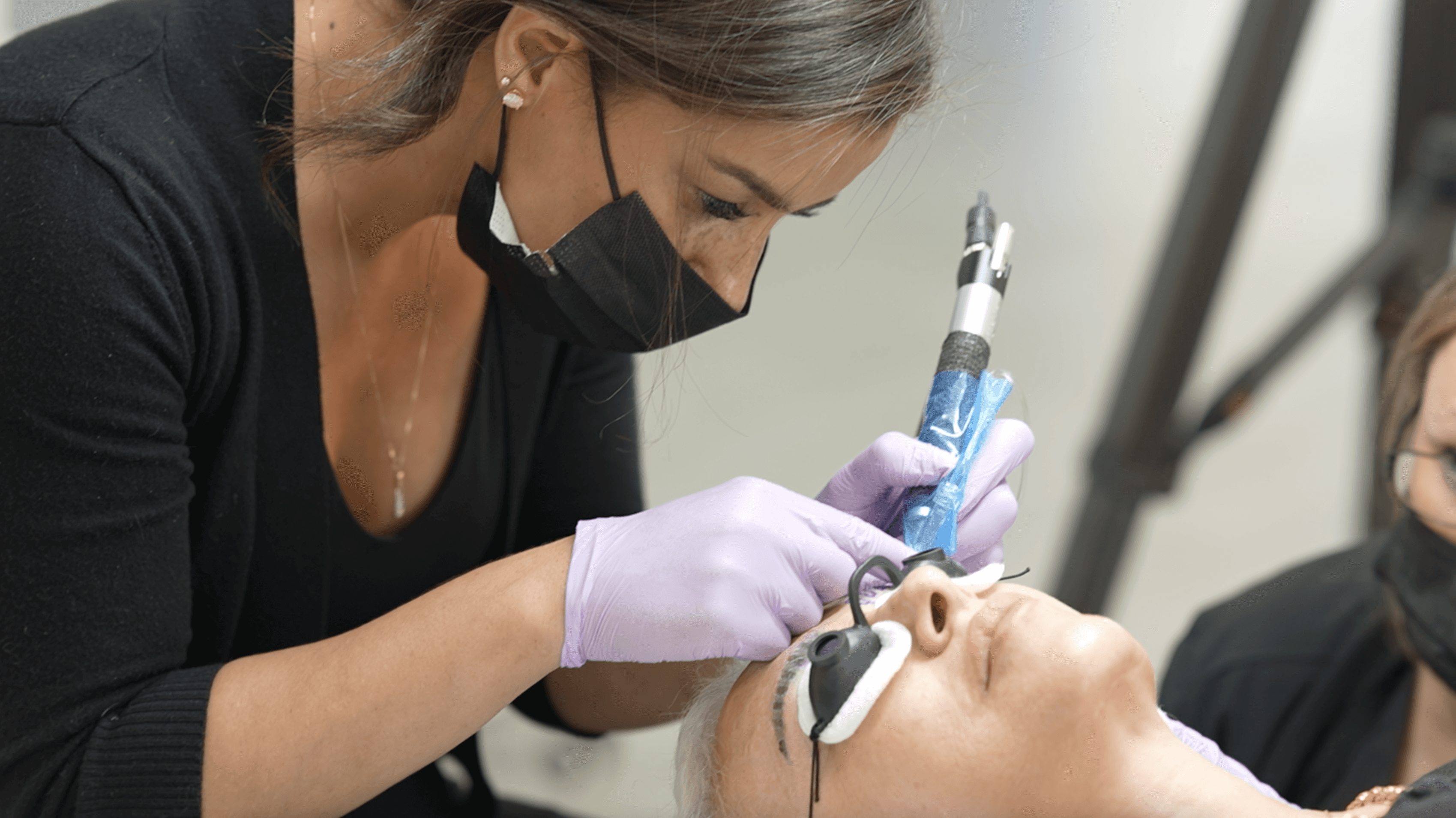 Especialista realizando un tratamiento de remoción en las cejas de una clienta