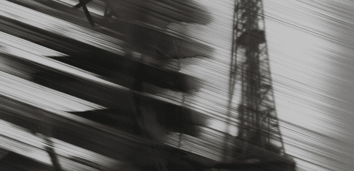 A blurred black-and-white image capturing the motion of a structure resembling a tower or crane, evoking speed, transition, and indus
