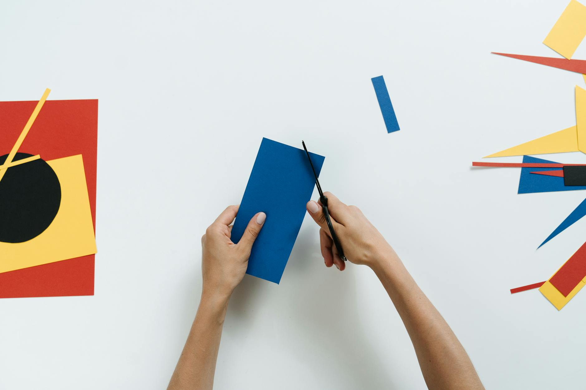 A top-down view of a teacher arranging colorful plastic blocks and sorting trays on a classroom rug.