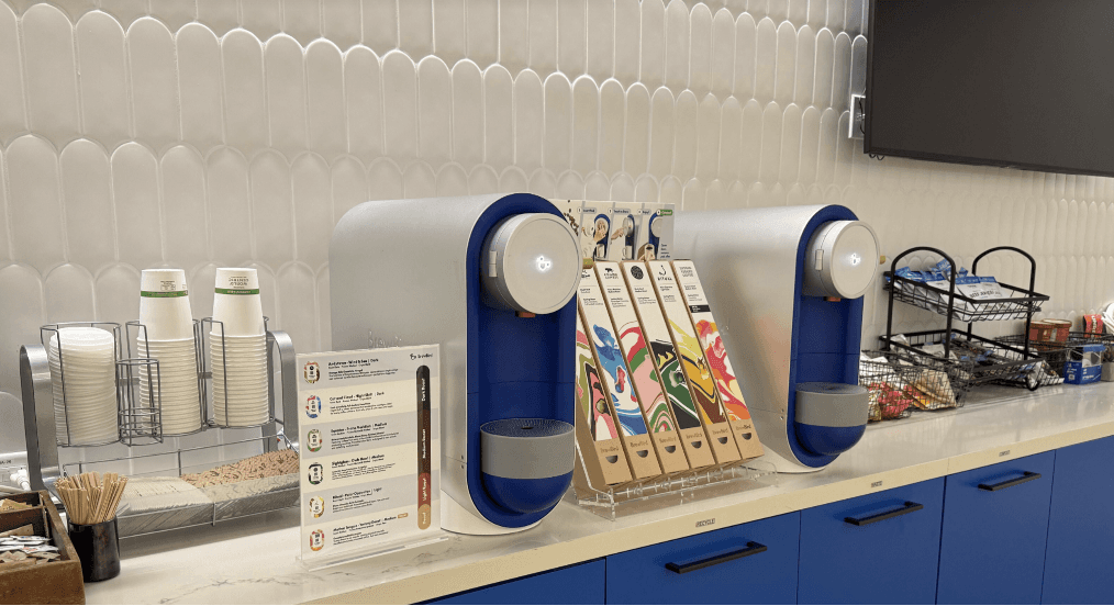 Title: Two BrewBird brewers on one counter - Description: Two blue BrewBird brewers placed on a counter in a higher-traffic office area.