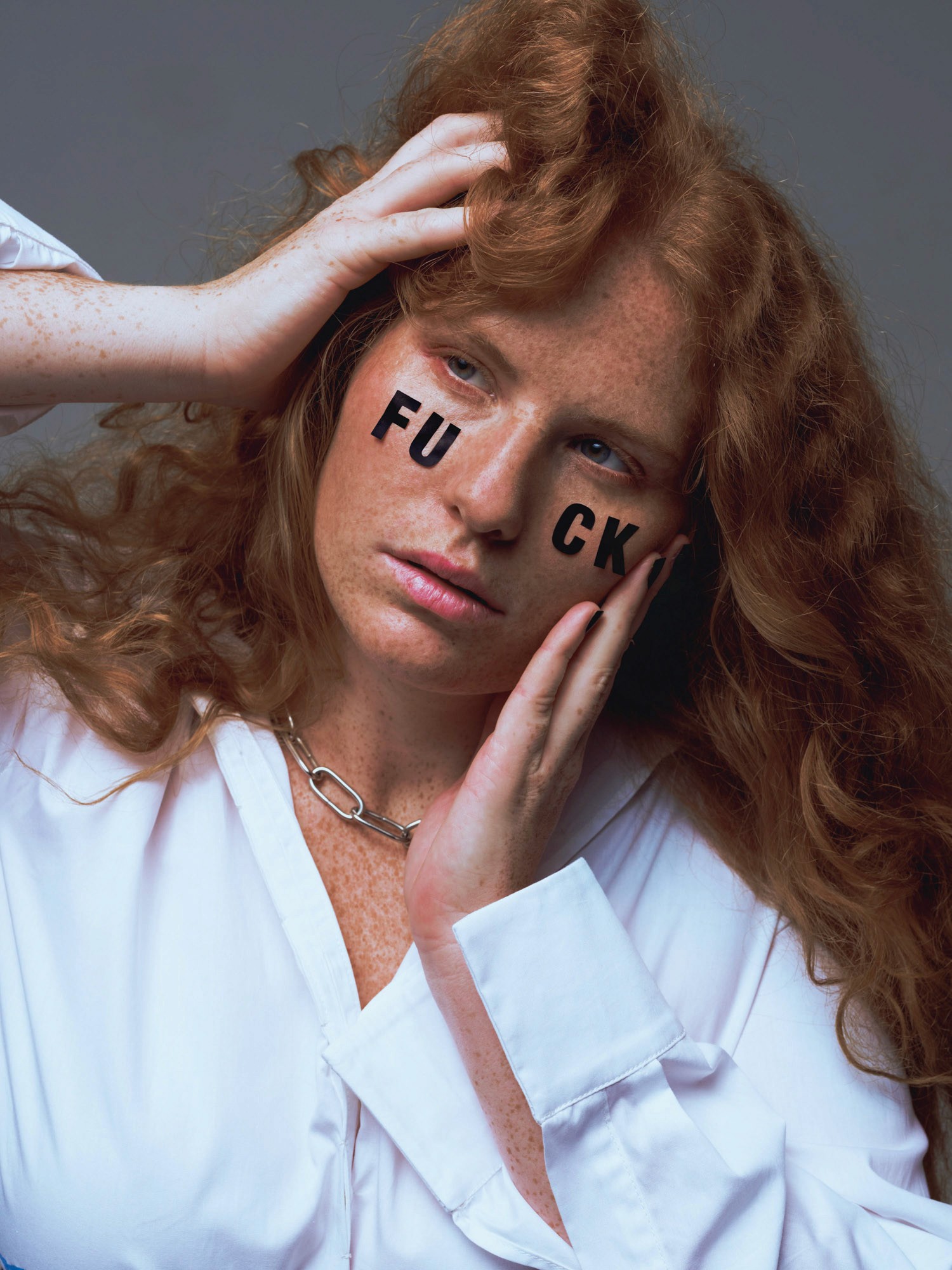 A brown-haired person wearing a white shirt strikes a dramatic pose in front of flashing lightning, their hands partially covering their face. The letters F, U, C, K stand out prominently in the scene.
