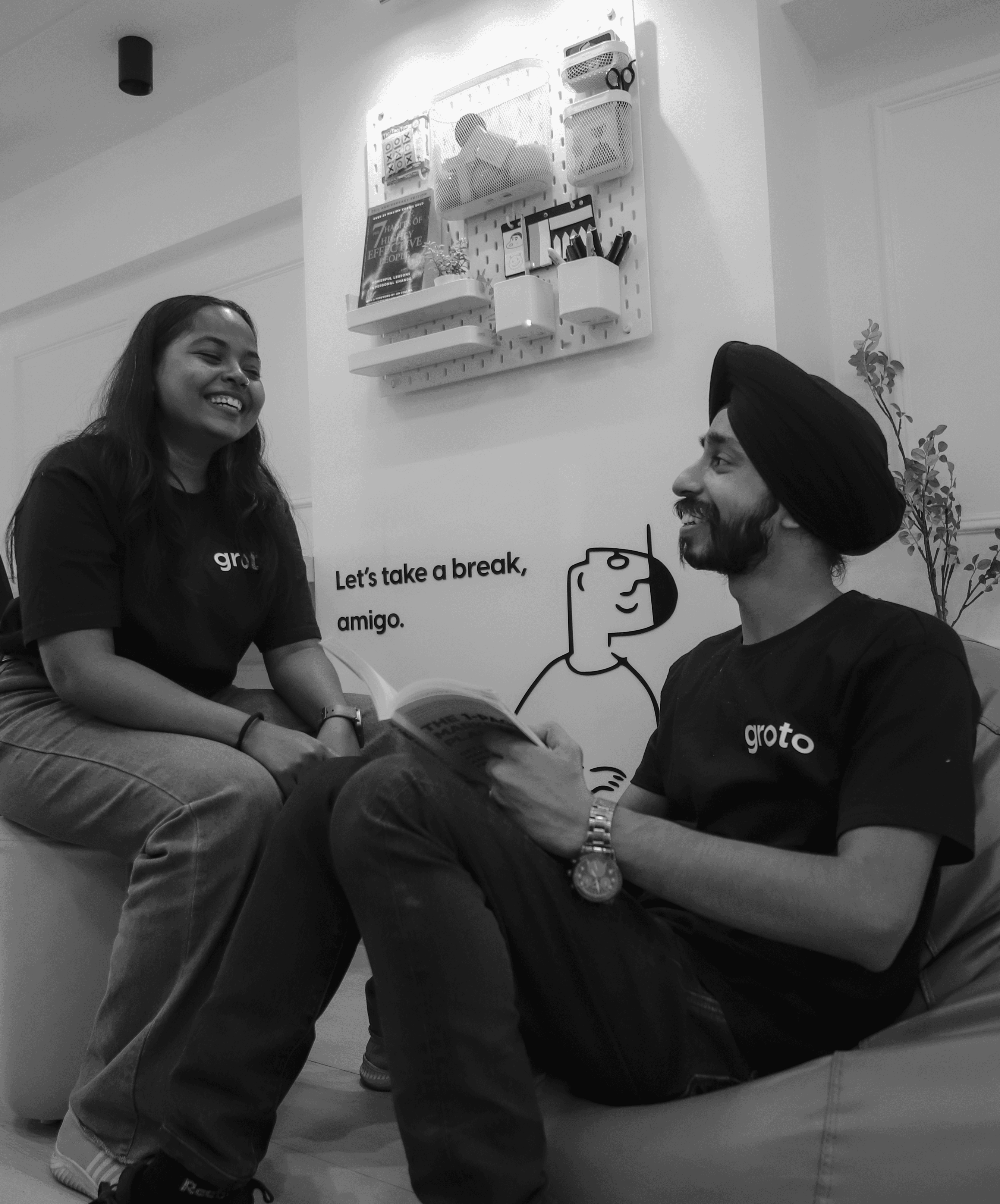Black and white photo of two people looking at a computer screen with papers on wall