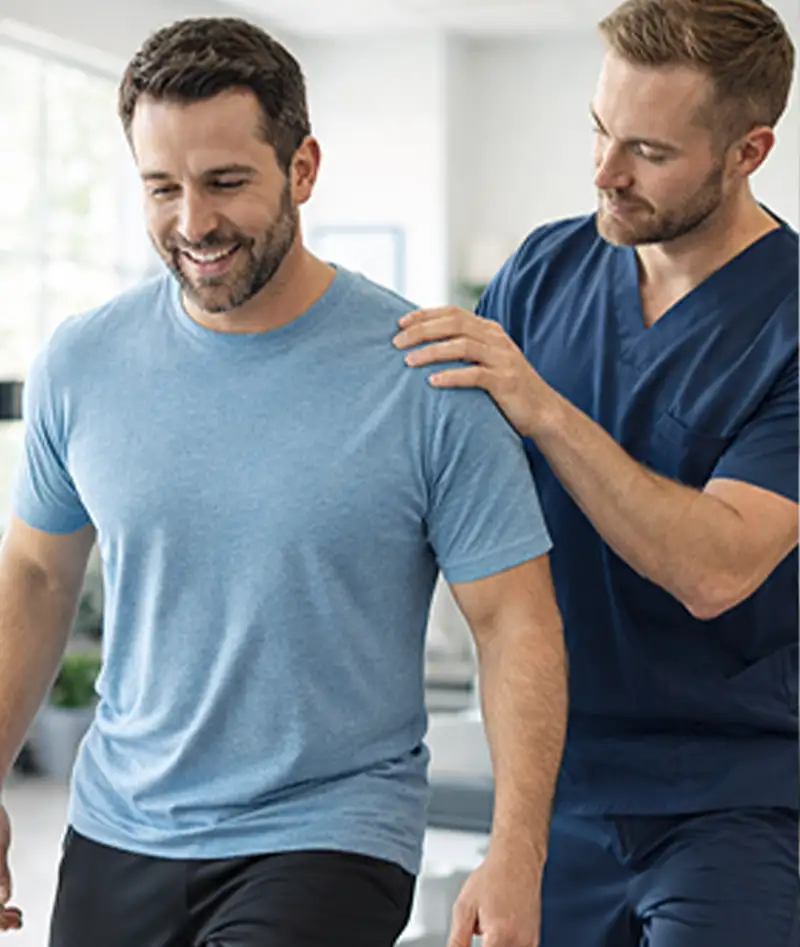 Chiropractor guiding a male patient through a walking rehabilitation exercise during treatment at AMIT Clinics in Kaysville, Utah