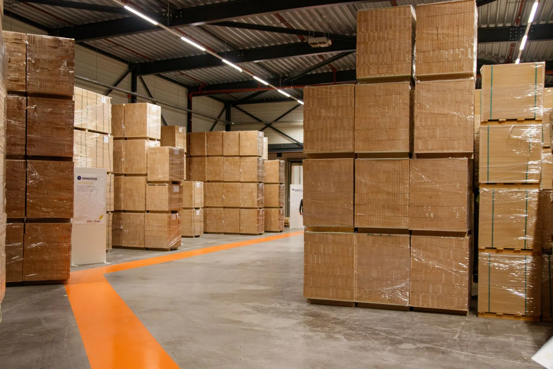 Stacked cardboard boxes on pallets along a warehouse aisle