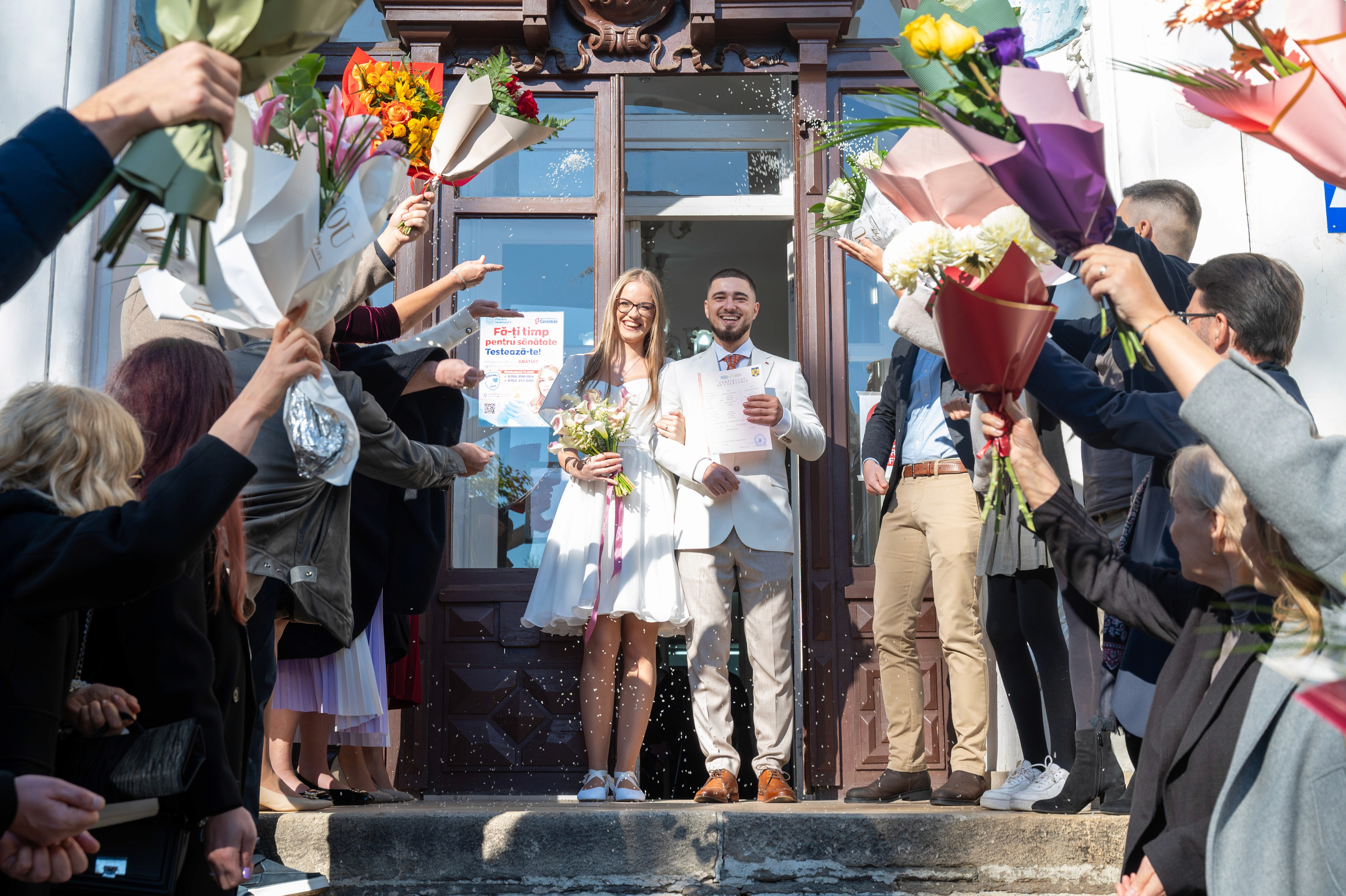 Ieşirea soțului și a soției de la starea civilă, întâmpinați de invitați.