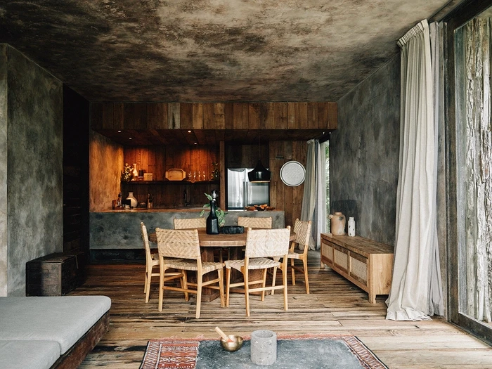 Premier Suite at Nômade Tulum highlighting part of the bed with pillow and cushion, and bright and beautiful lamp next to the bed.