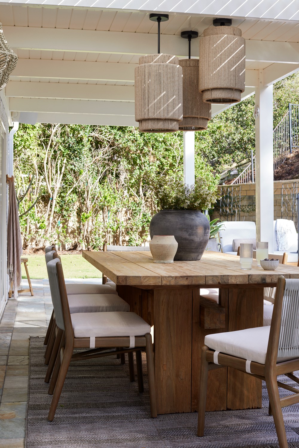 This beautifully landscaped outdoor space features a cozy patio, stylish dining set, and an eight-person wooden table, perfect for relaxation and entertaining