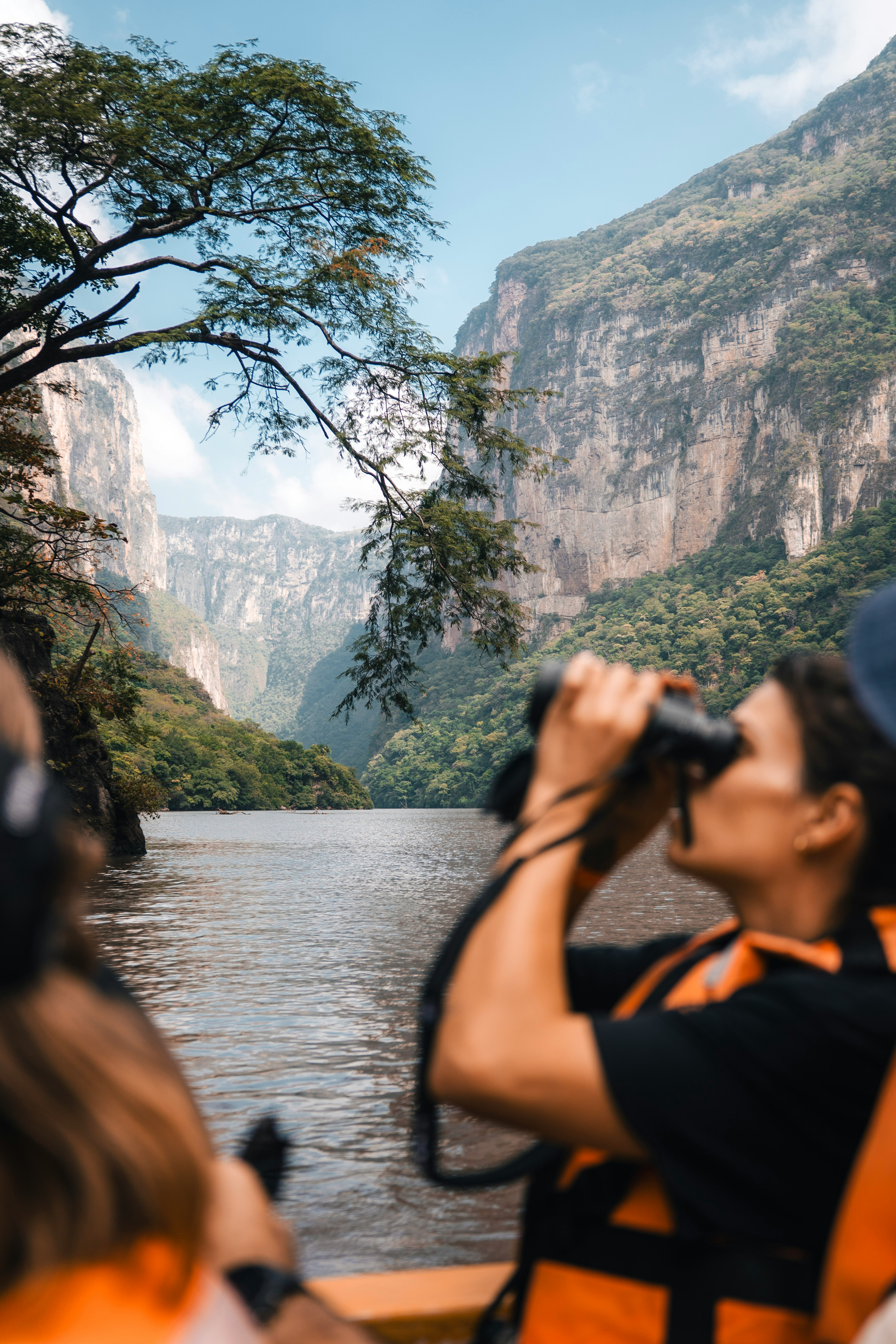 Woman with binoculars on a boat in a canyon