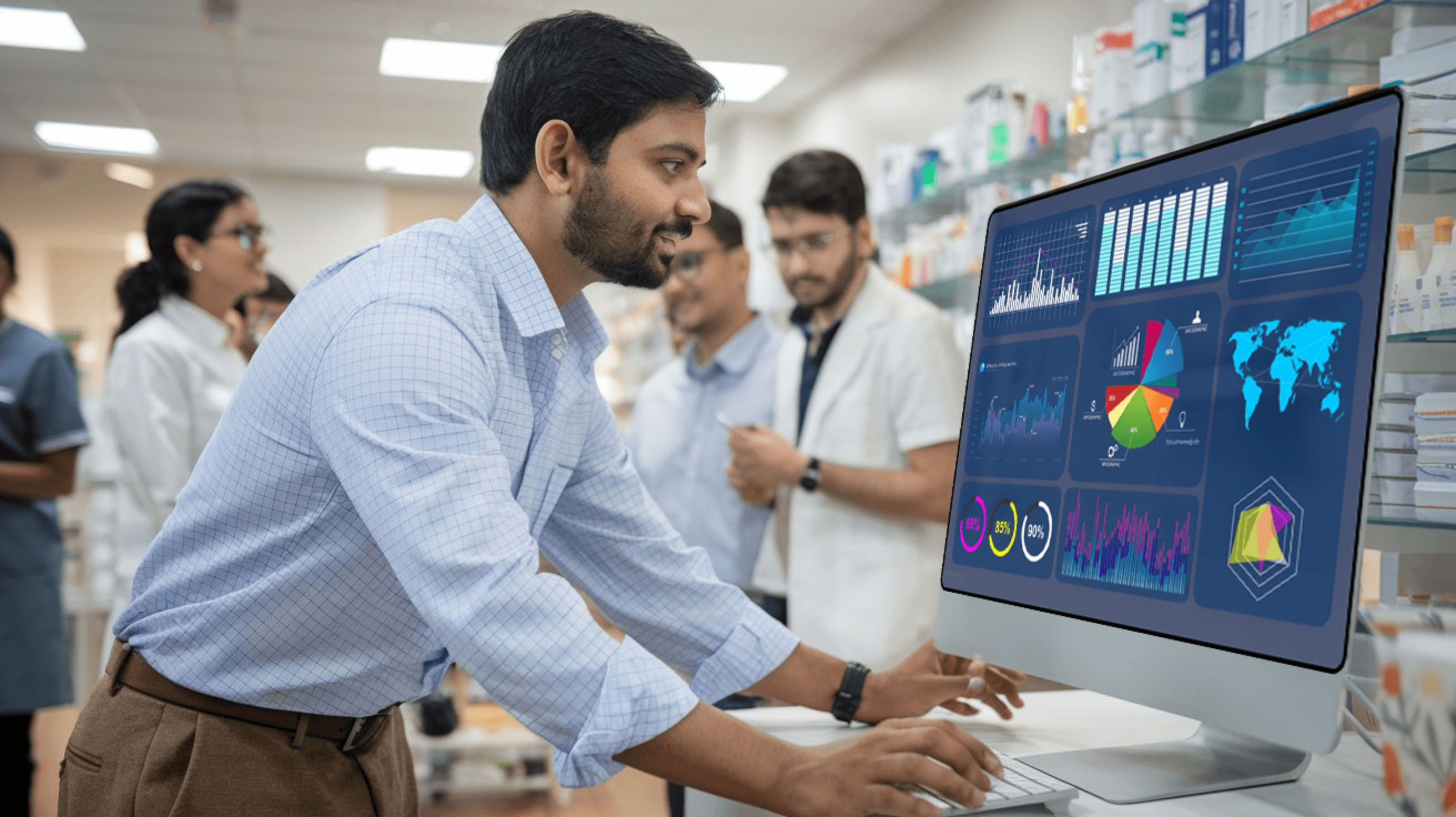 ndian pharmacist reviewing analytics on a computer screen in a pharmacy, showcasing digital transformation through SaaS solutions.