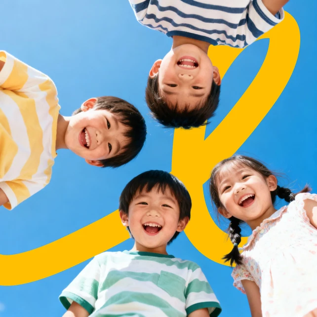 Four children in colorful striped shirts stand in a circle, smiling joyfully against a clear blue sky. A large, yellow letter "v" is in the background.