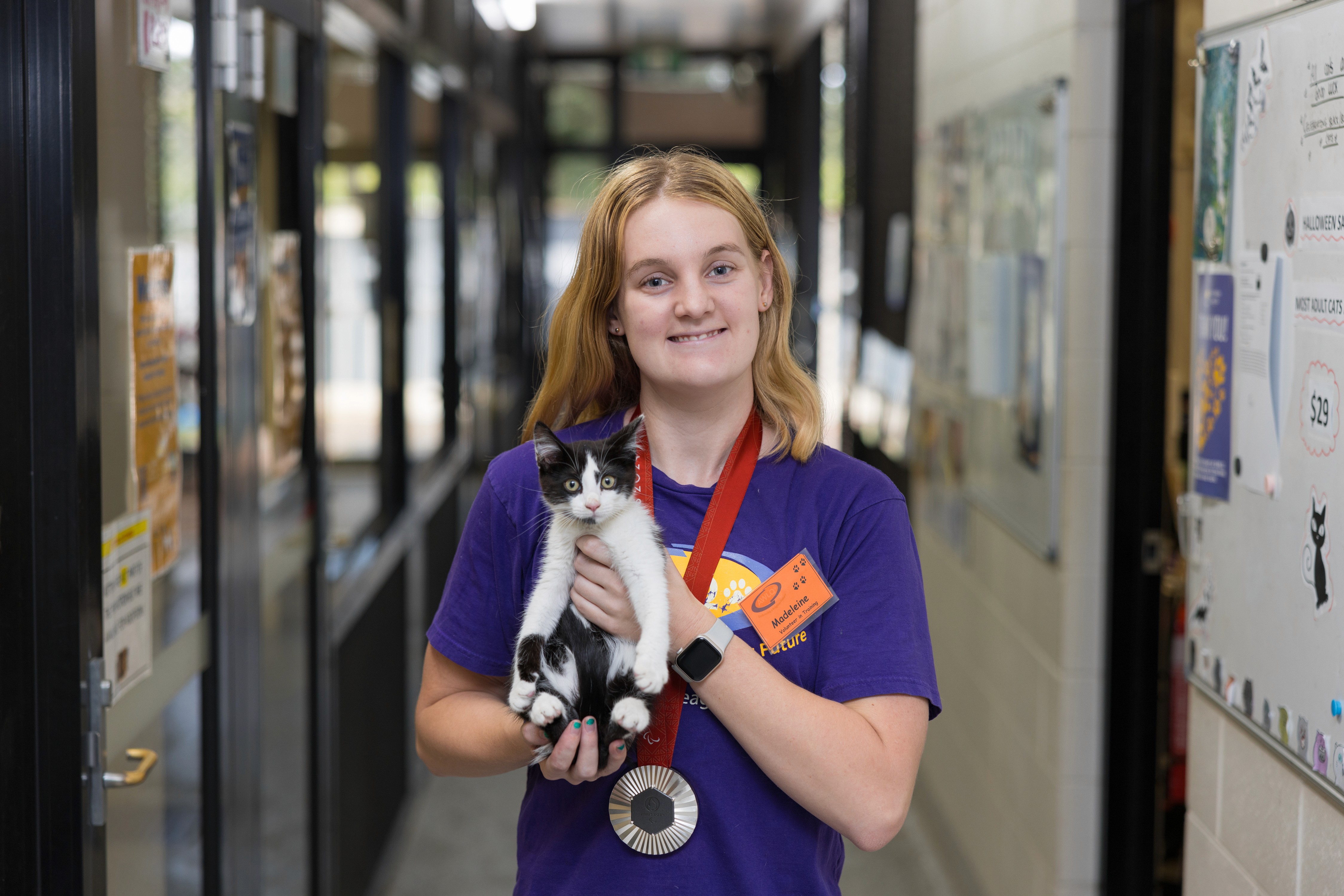 Animal shelter volunteer holding a black and white kitten