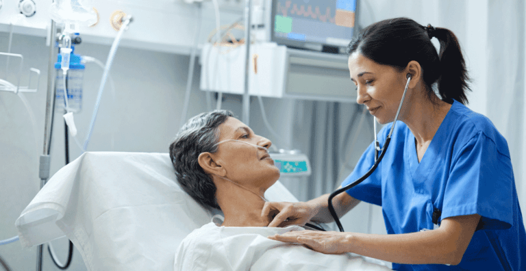 Nurse using a stethoscope to check a patient lying in a hospital bed.