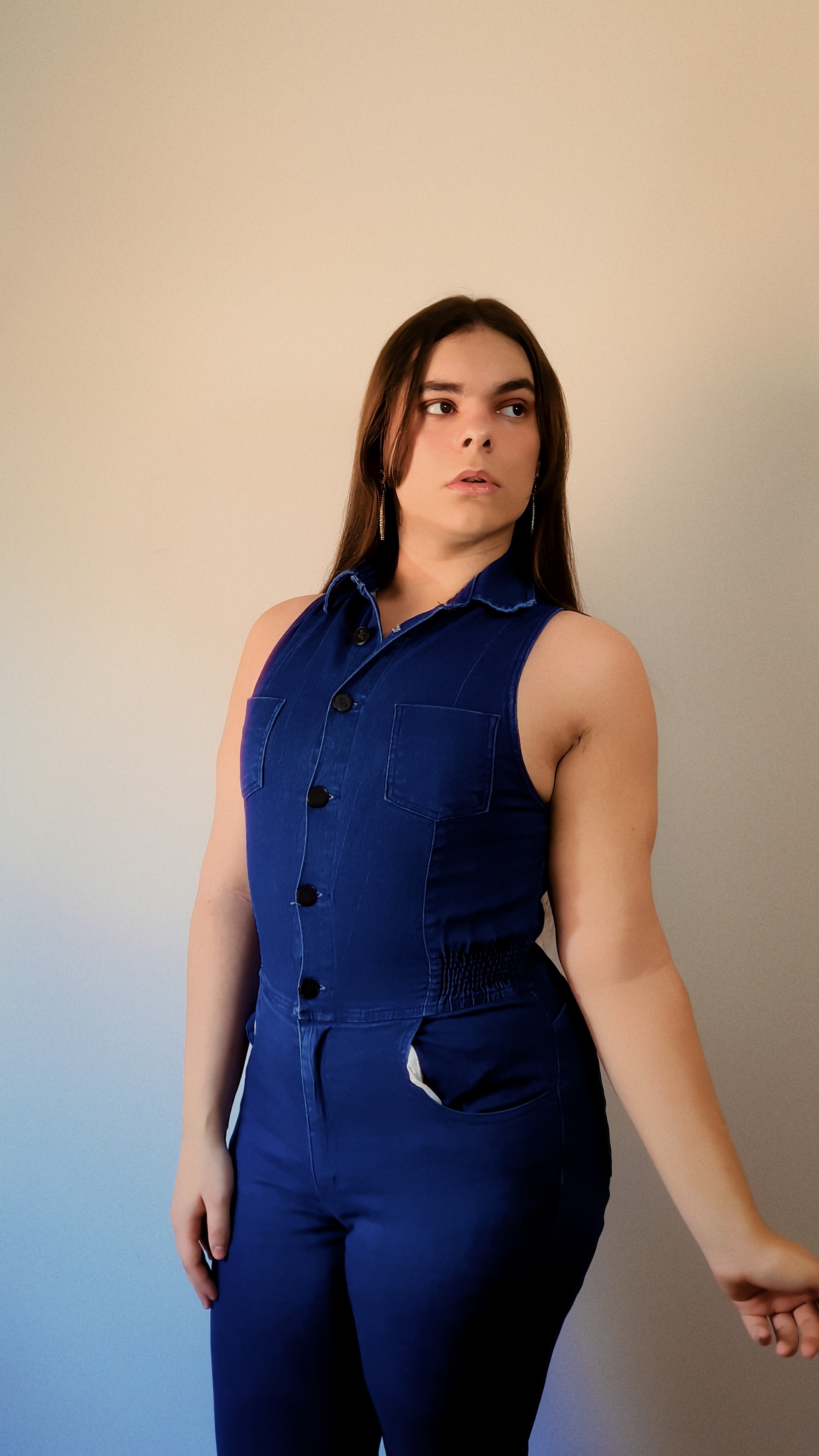 Fotografia de Daniela Vigarani, Social Media Creative Strategist especializada no mercado de games, vestindo blusa azul em um fundo de tons quentes, na capa de seu portfólio profissional.