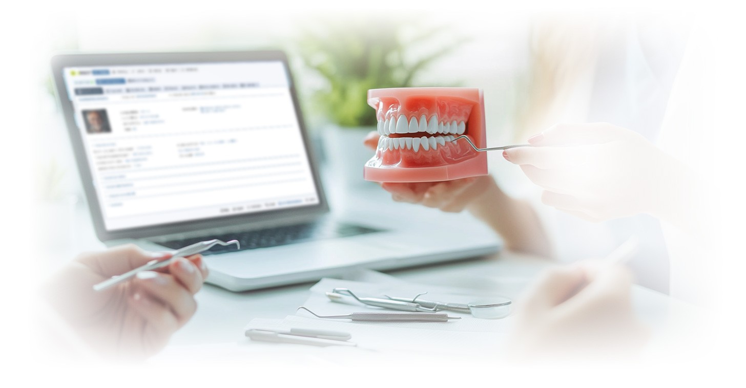 Proteză dentară lângă un laptop cu dROOT pentru gestionarea digitală a pacienților.