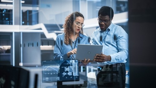 Man and woman looking at laptop in tech environment