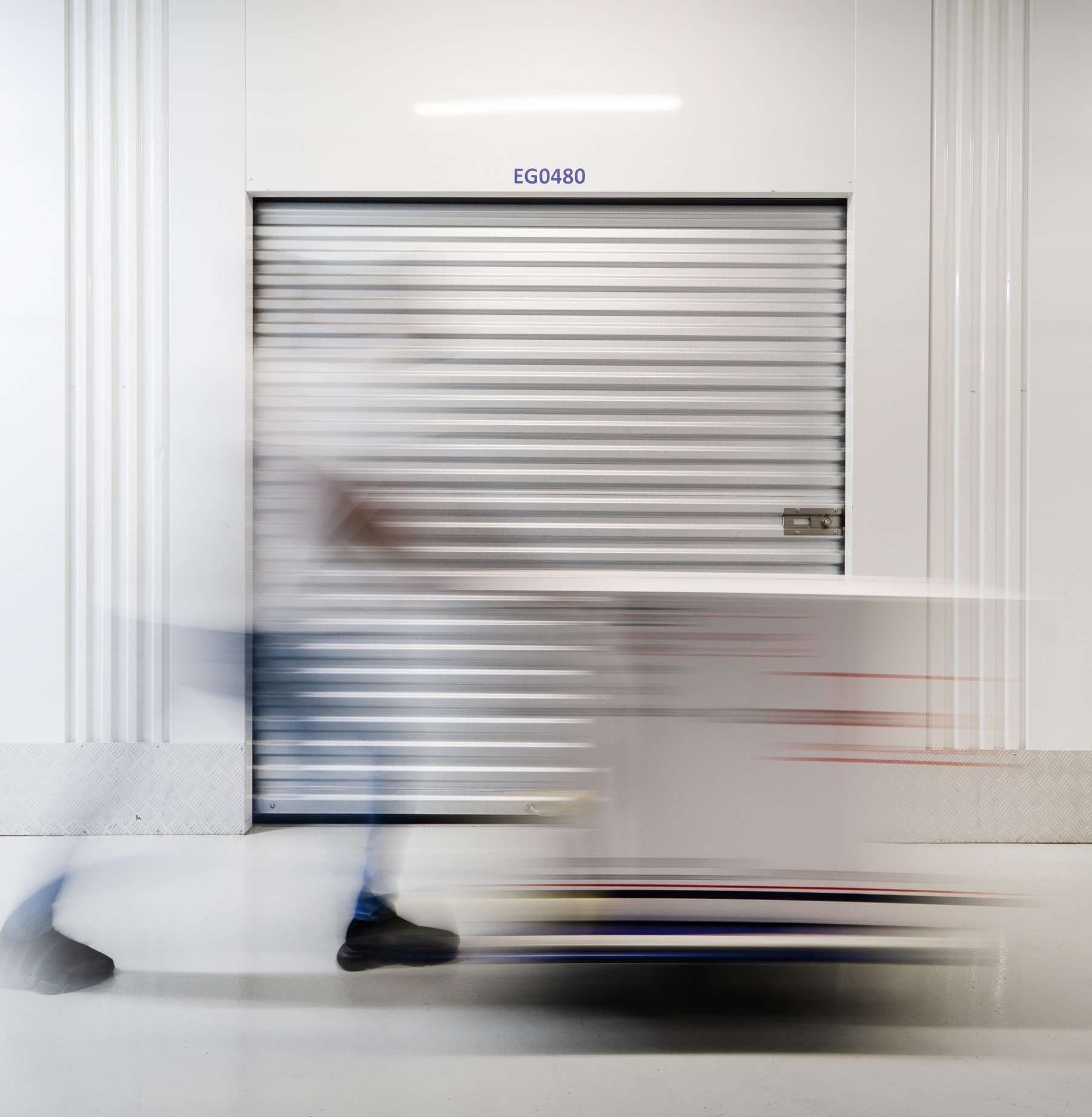 A blurred-out image of an Extra Space employee pushing a trolley of boxes in the storage facility. 