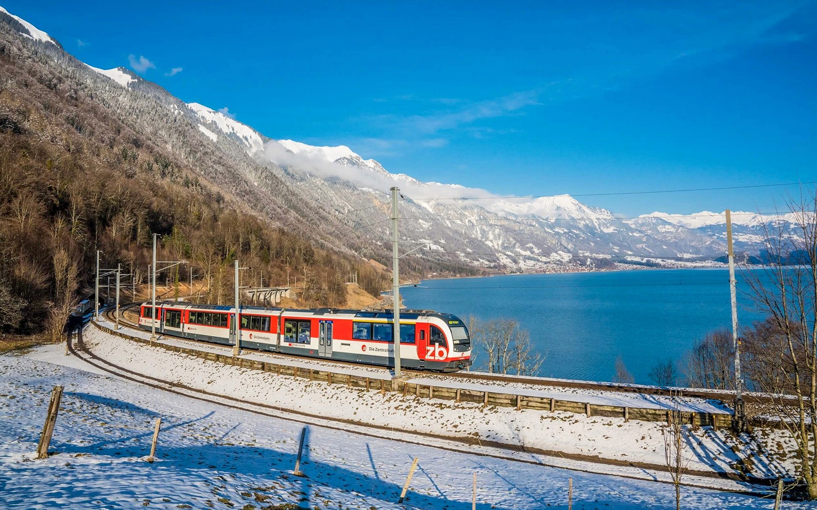 Train on Lucerne–Interlaken Express route with snowy mountains and lake views.