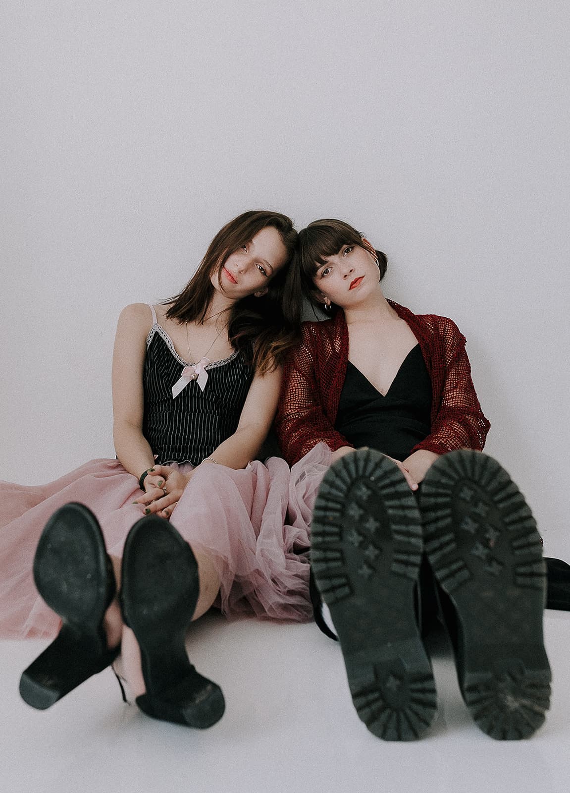 Two models sitting on the floor, wearing contrasting outfits of black and pink tulle skirts, reflecting the 90s vintage fashion at Revelator Studio, a natural light studio in Shreveport.