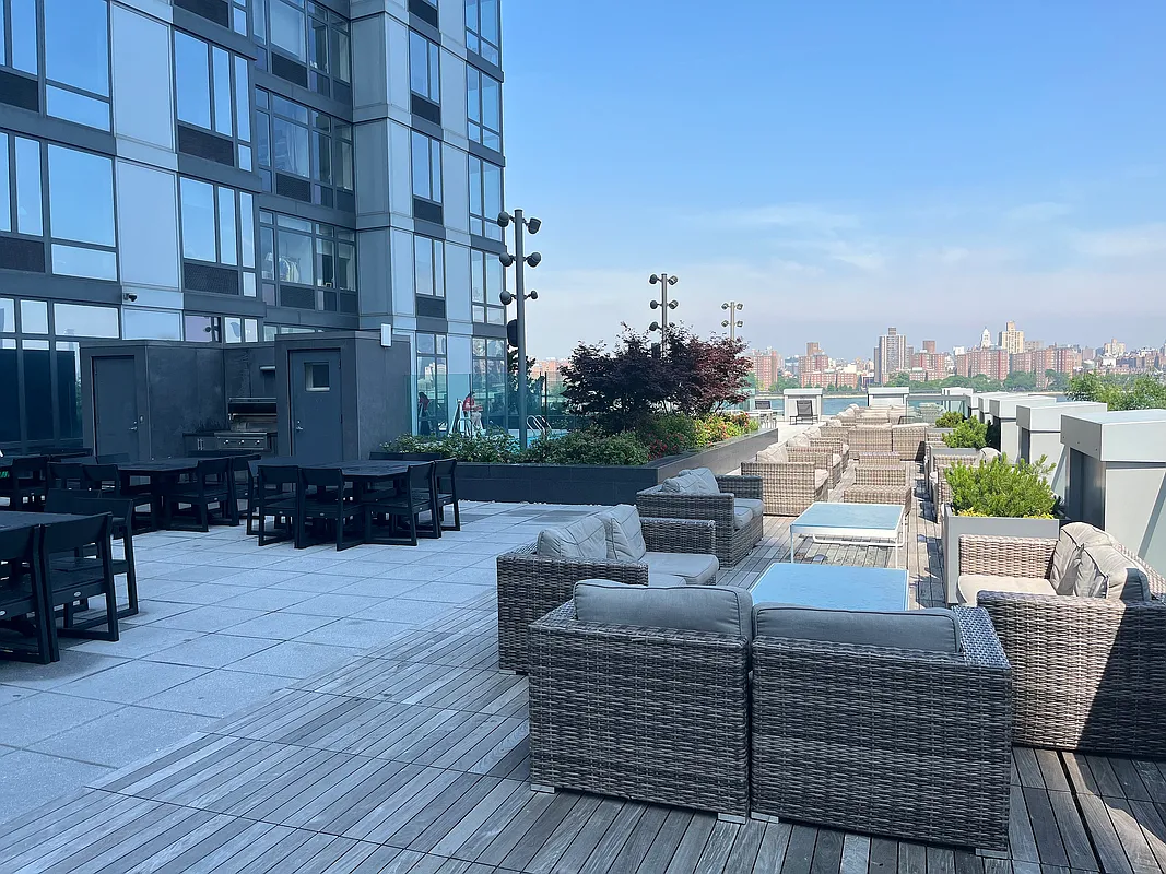 Rooftop patio featuring wicker furniture and a panoramic view of the city skyline.