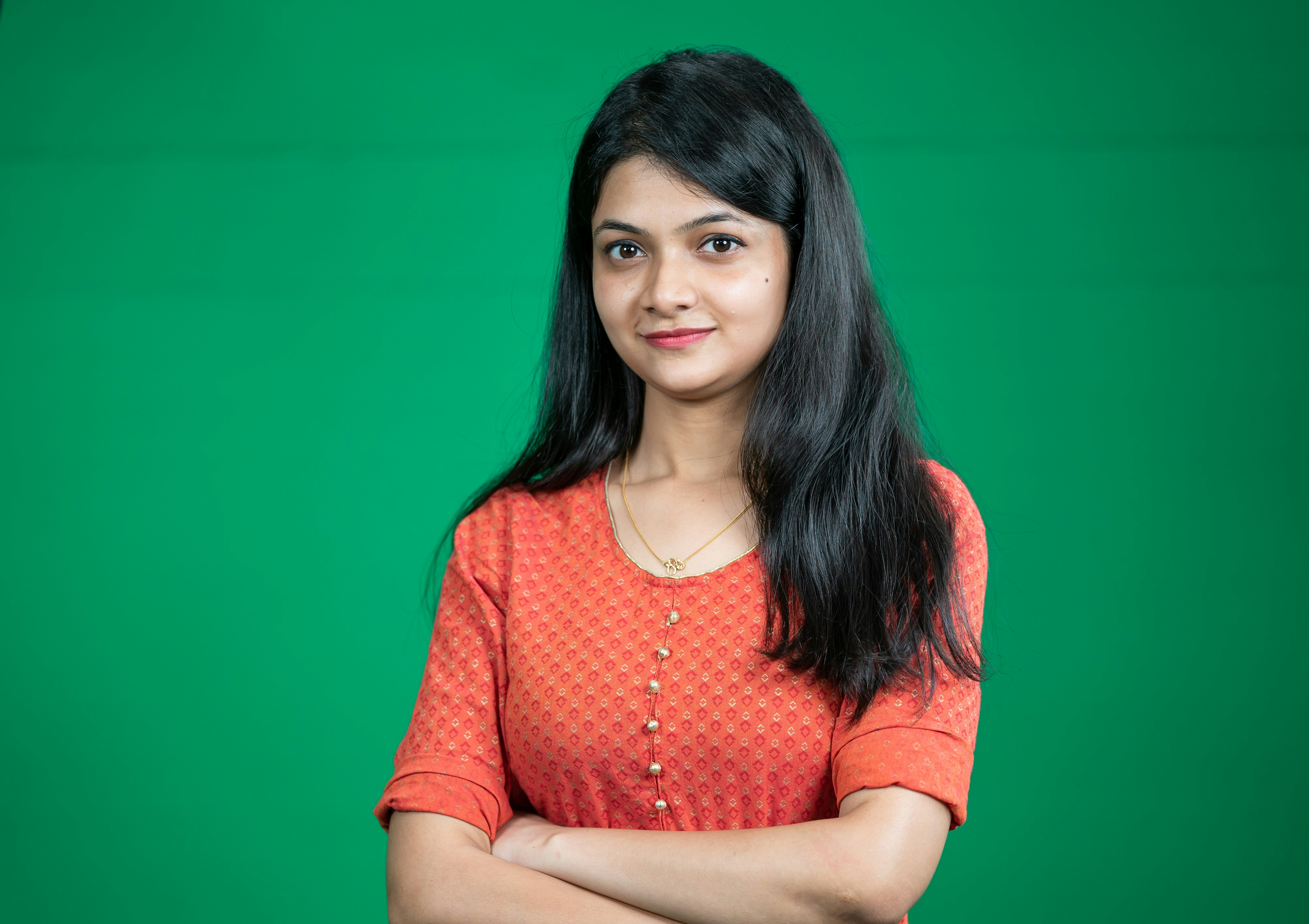 a woman standing with her arms crossed in front of a green background