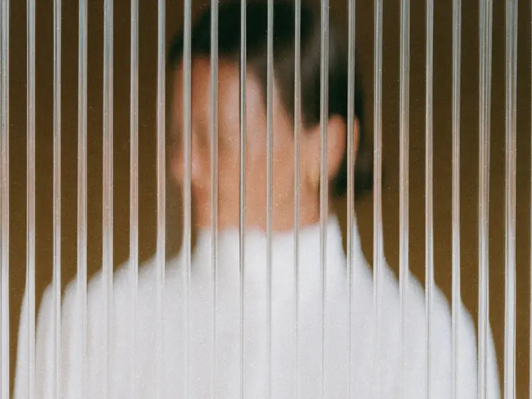 Person obscured behind textured privacy glass.