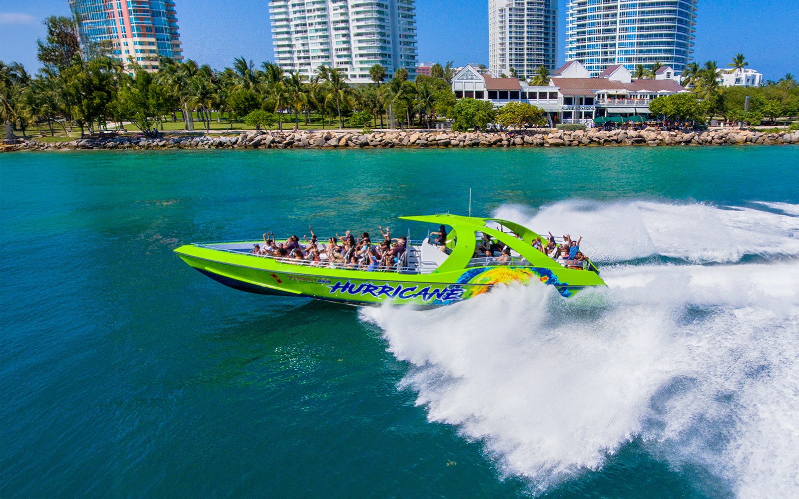 Speedboat with tourists cruising near Miami waterfront skyscrapers.