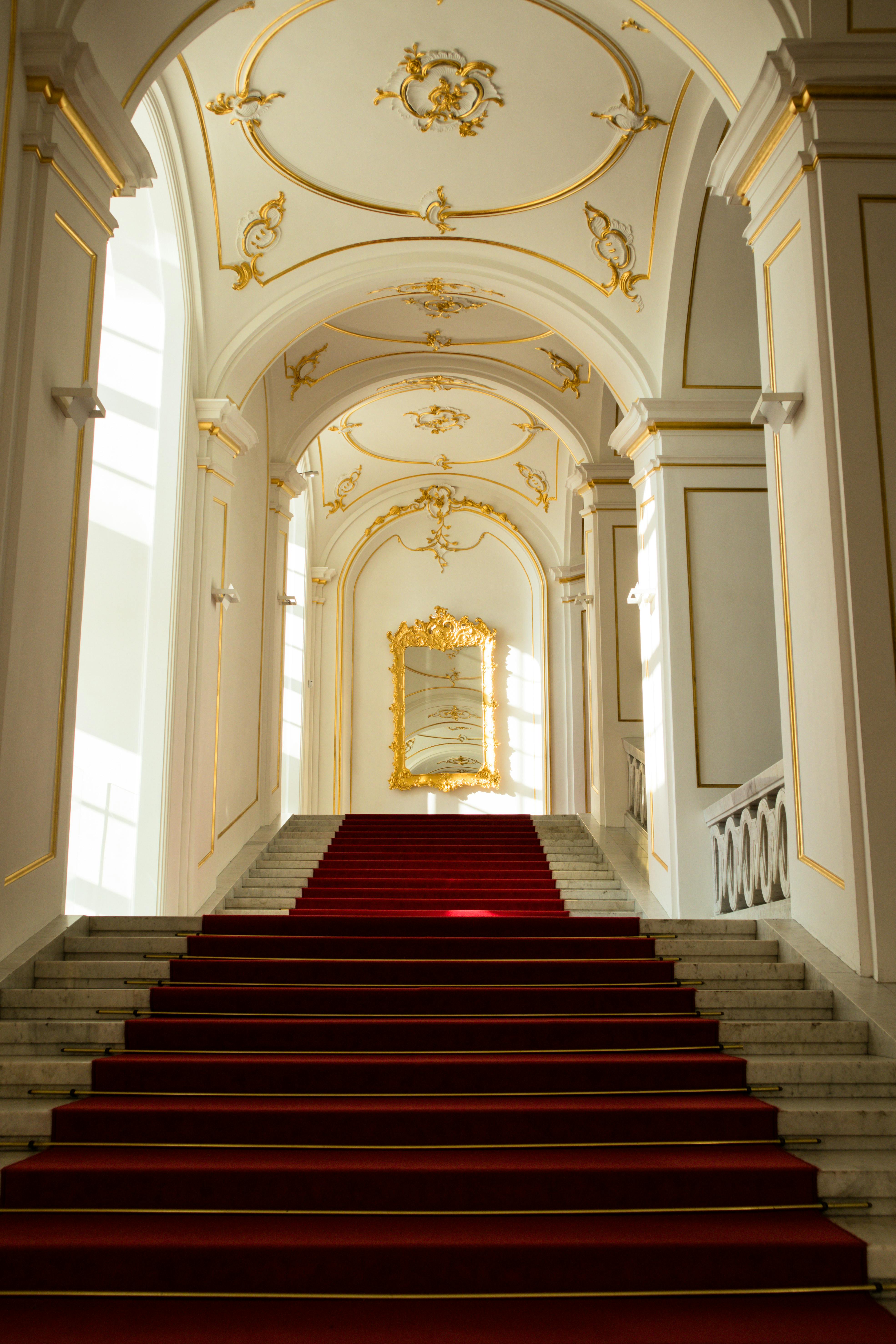 An exterior view through an open doorway showing a white-themed sofa inside, with statues placed on both sides of the entrance wall.