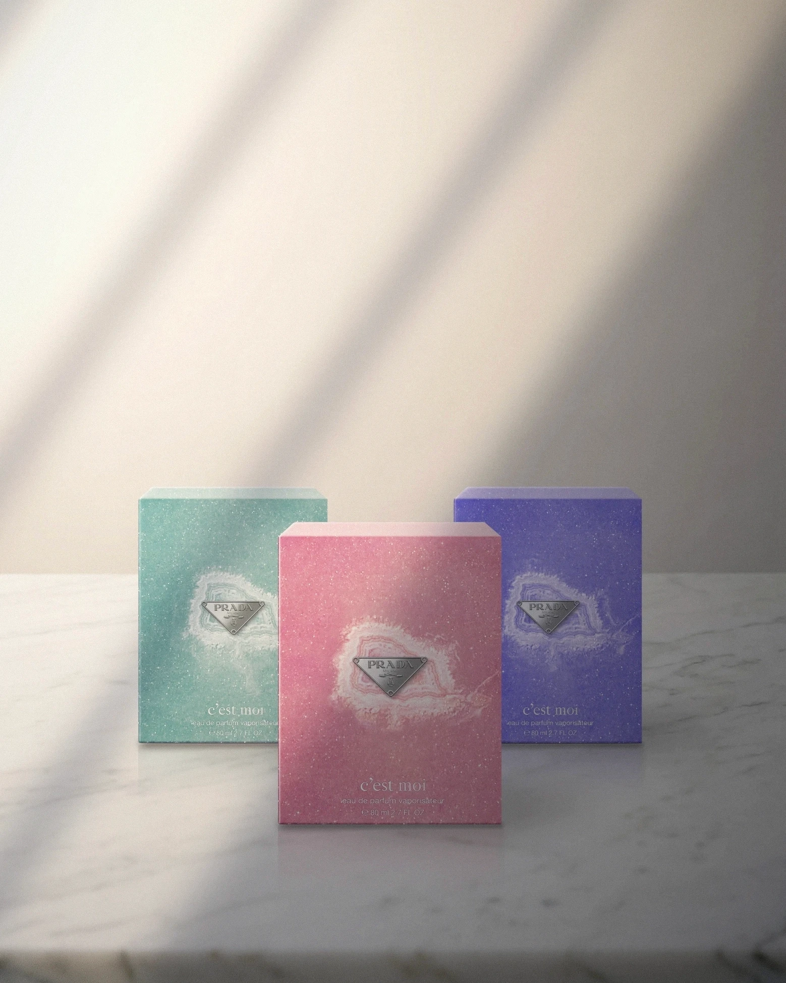 Three boxes in aqua green, pink and violet standing together on marble